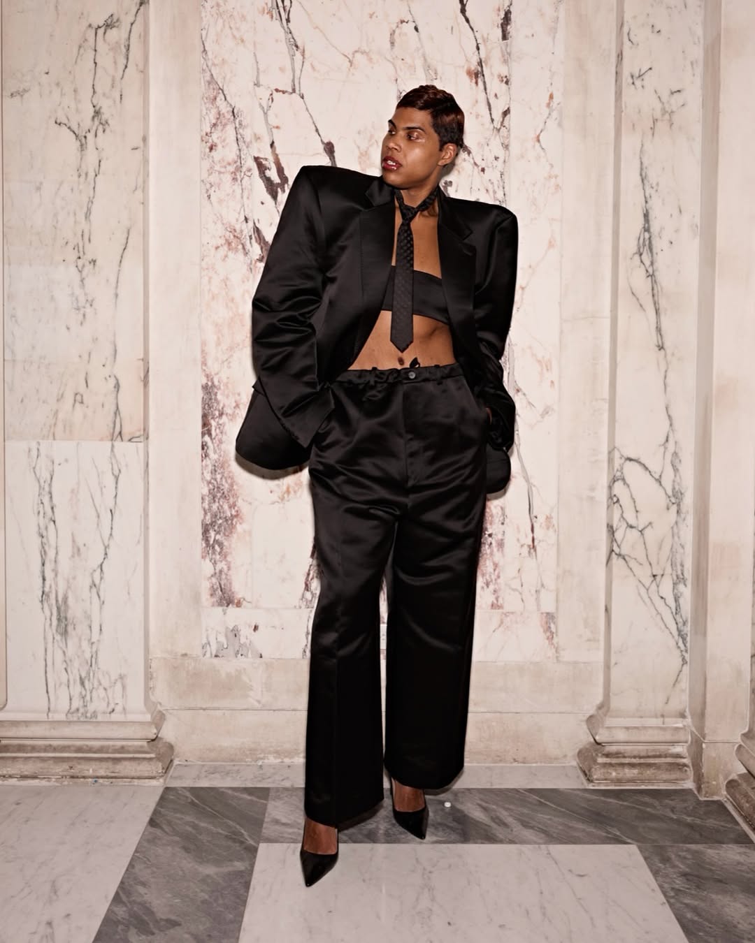 Set against a marble pillar, EJ poses with hands in pockets and a gaze off to the side. The strong silhouette and boxy blazer create a commanding, editorial-worthy stance. | Source: Instagram/ejjohnson_