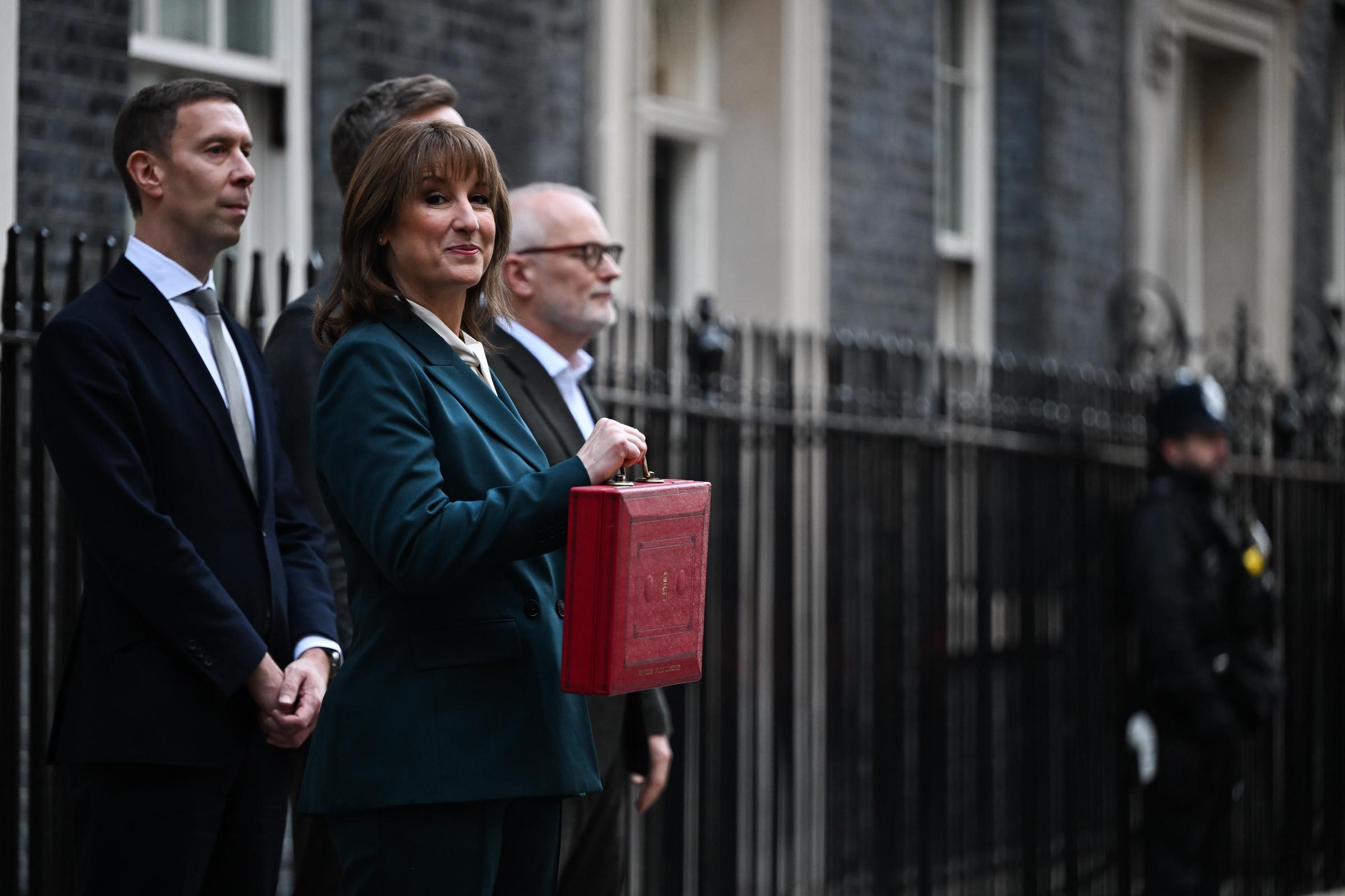 Standing outside Number 11 with the red Budget box firmly in hand, Rachel Reeves paused for the cameras moments before heading to the Commons. The Chancellor's smile — caught as she glanced to her right — came as a reporter's barrage of questions triggered a flurry of online commentary, making her expression one of the day's most talked-about images.