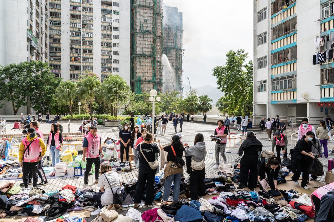 Volunteers distribute donated clothing to displaced residents near the burned towers of Wang Fuk Court in Hong Kong, on November 27, 2025 | Source: Getty Images