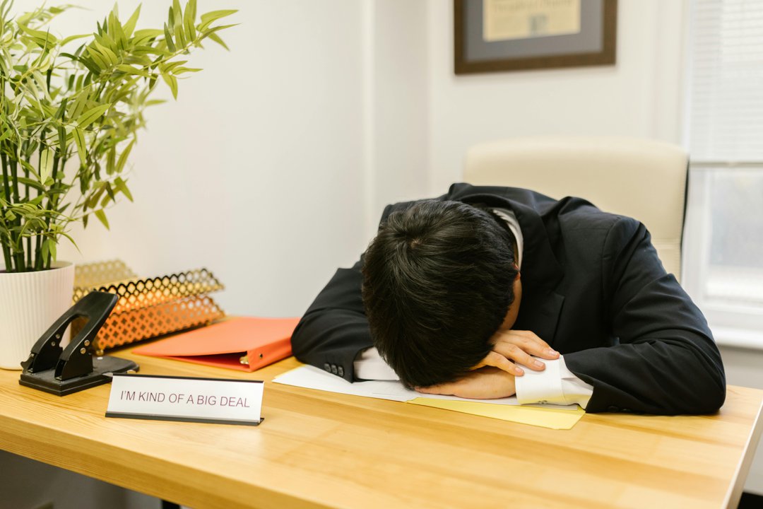 An exhausted man lying with his head on his desk | Source: Pexels