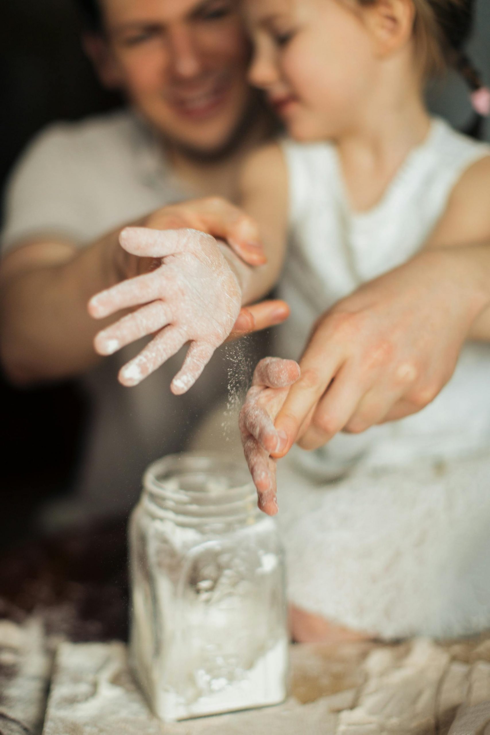 A little girl and her dad making dough with flour | Source: Pexels