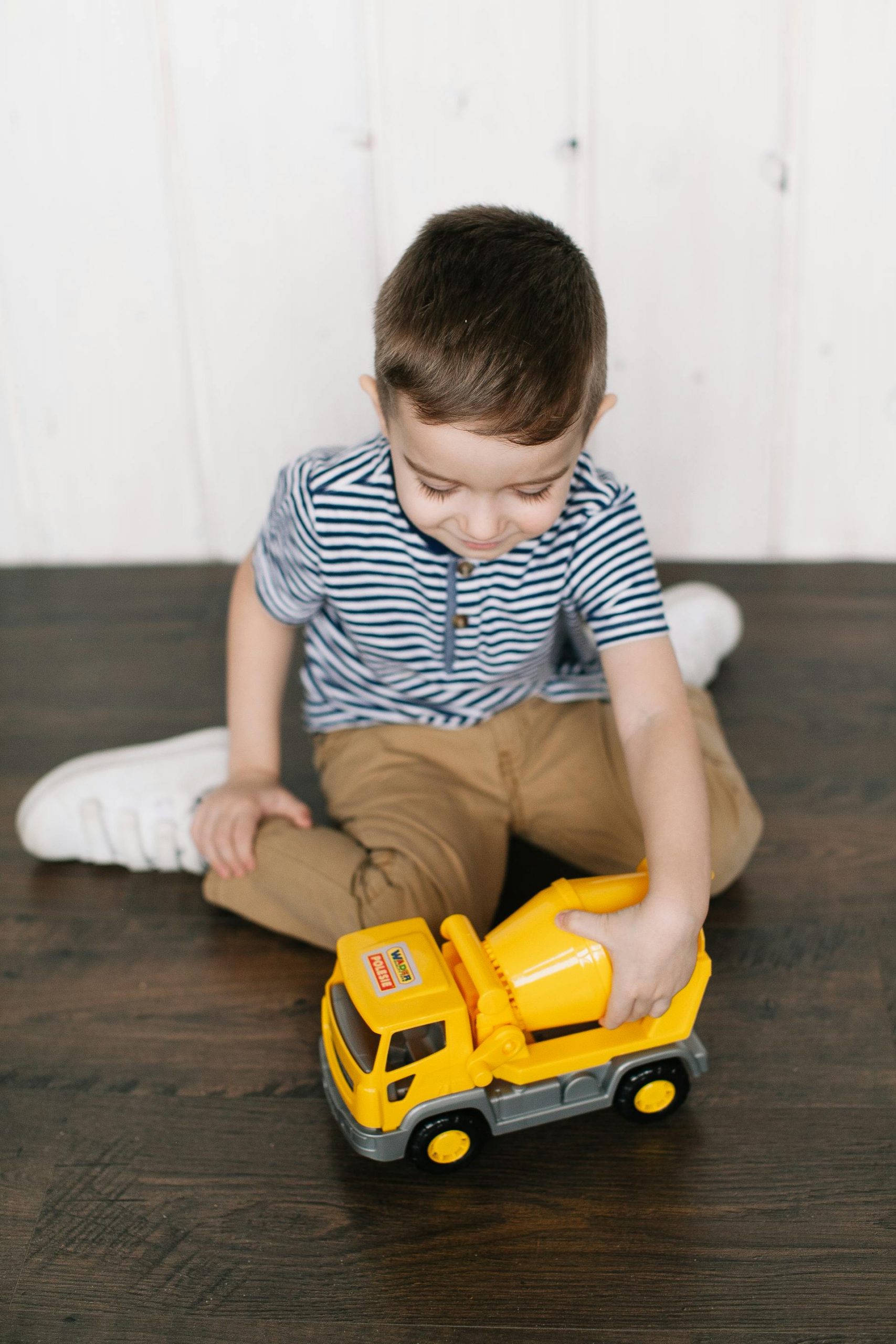 A little boy playing with a yellow plastic truck | Source: Pexels