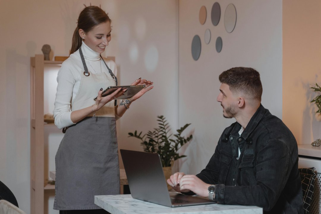 Woman in an apron talking to a male customer | Source: Pexels