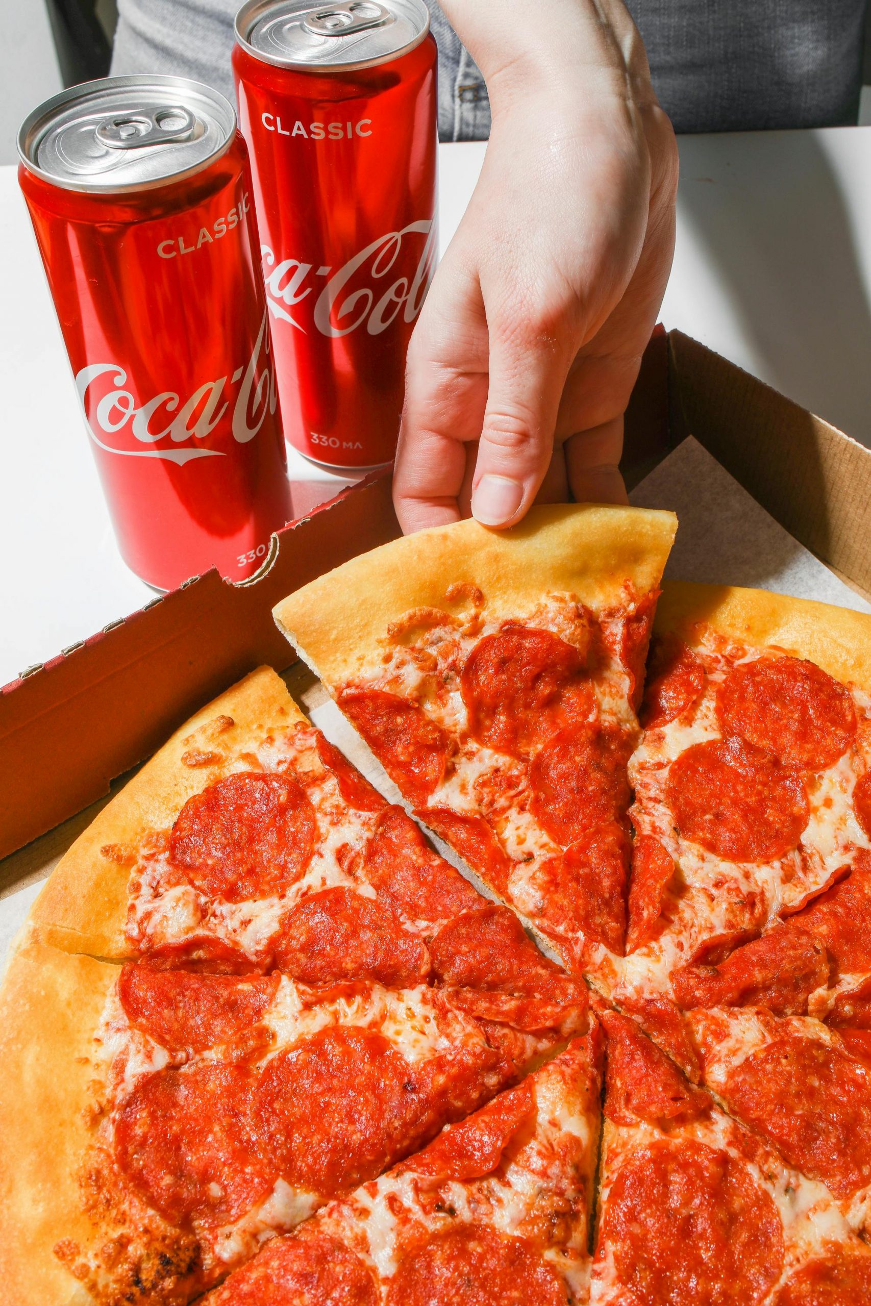 A person grabbing a slice of pizza | Source: Pexels