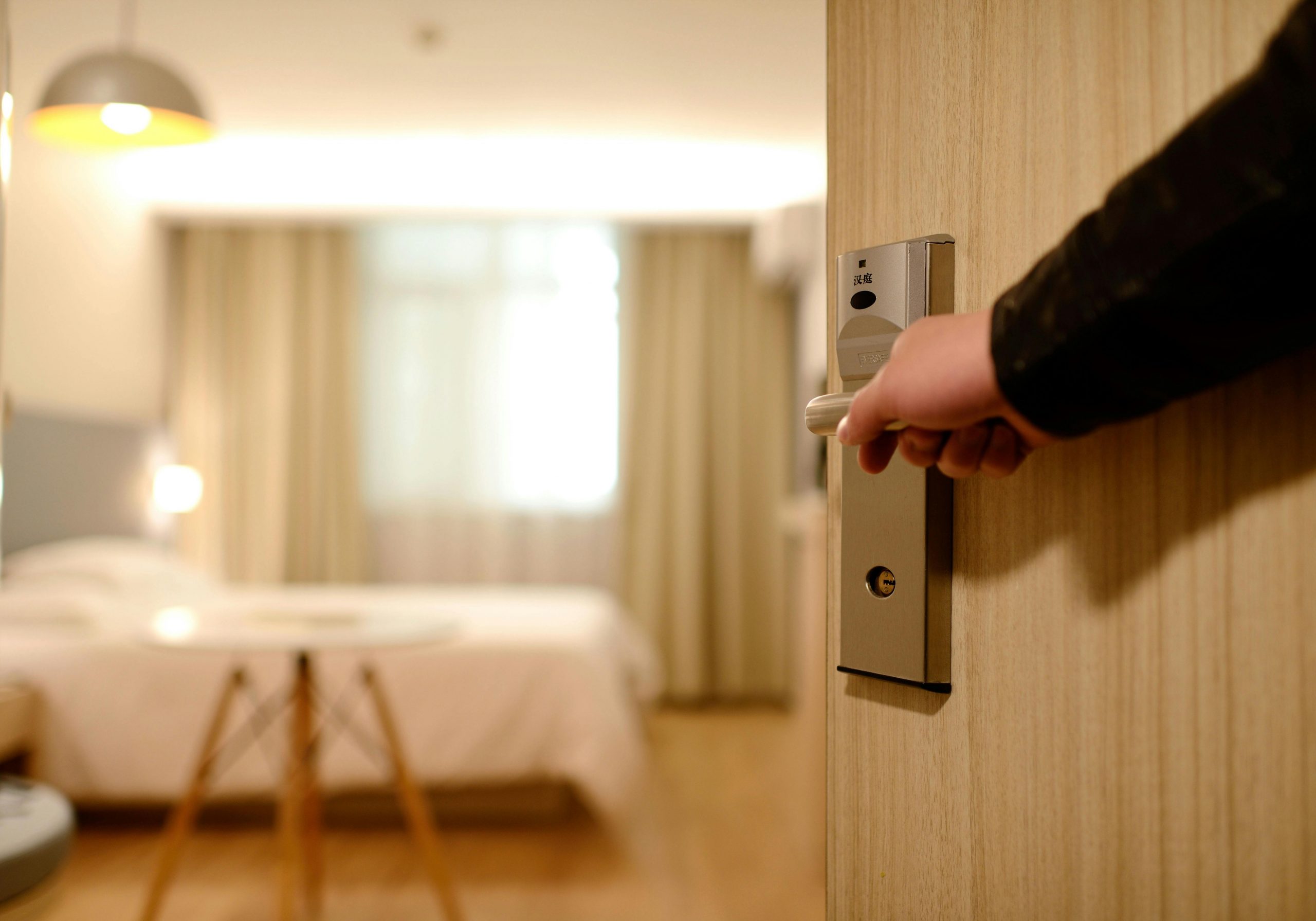 A man's hand on a bedroom door handle | Source: Pexels