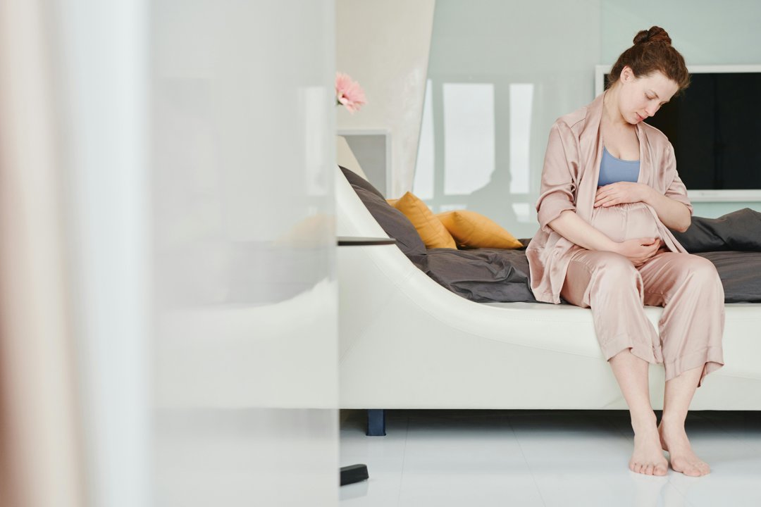 A woman sitting and cradling her pregnant belly | Source: Pexels