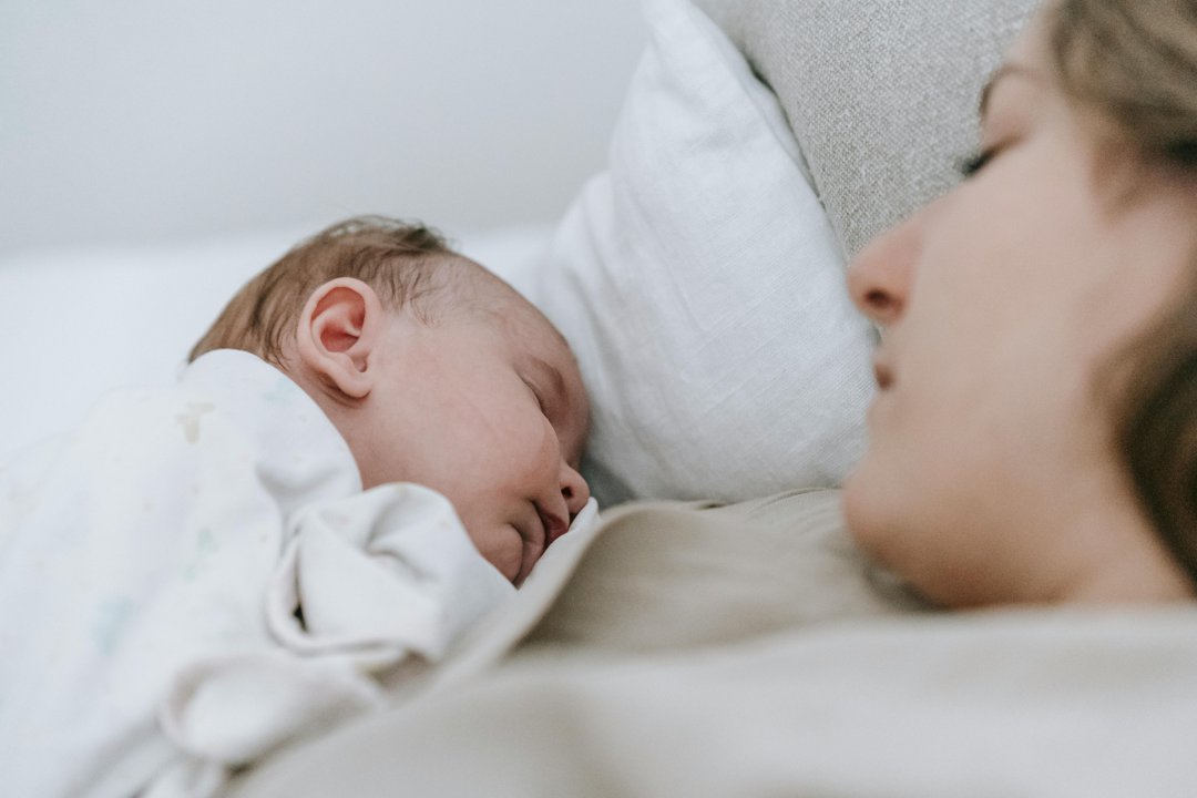 A woman sleeping with a baby | Source: Pexels