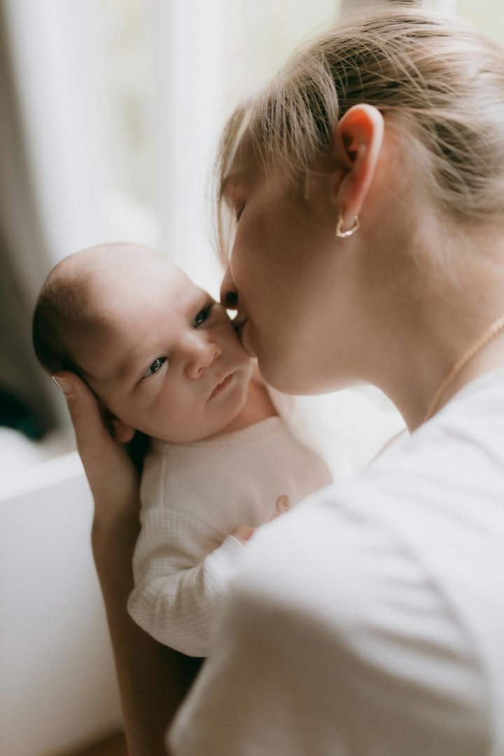 A mother kissing her newborn baby | Source: Pexels