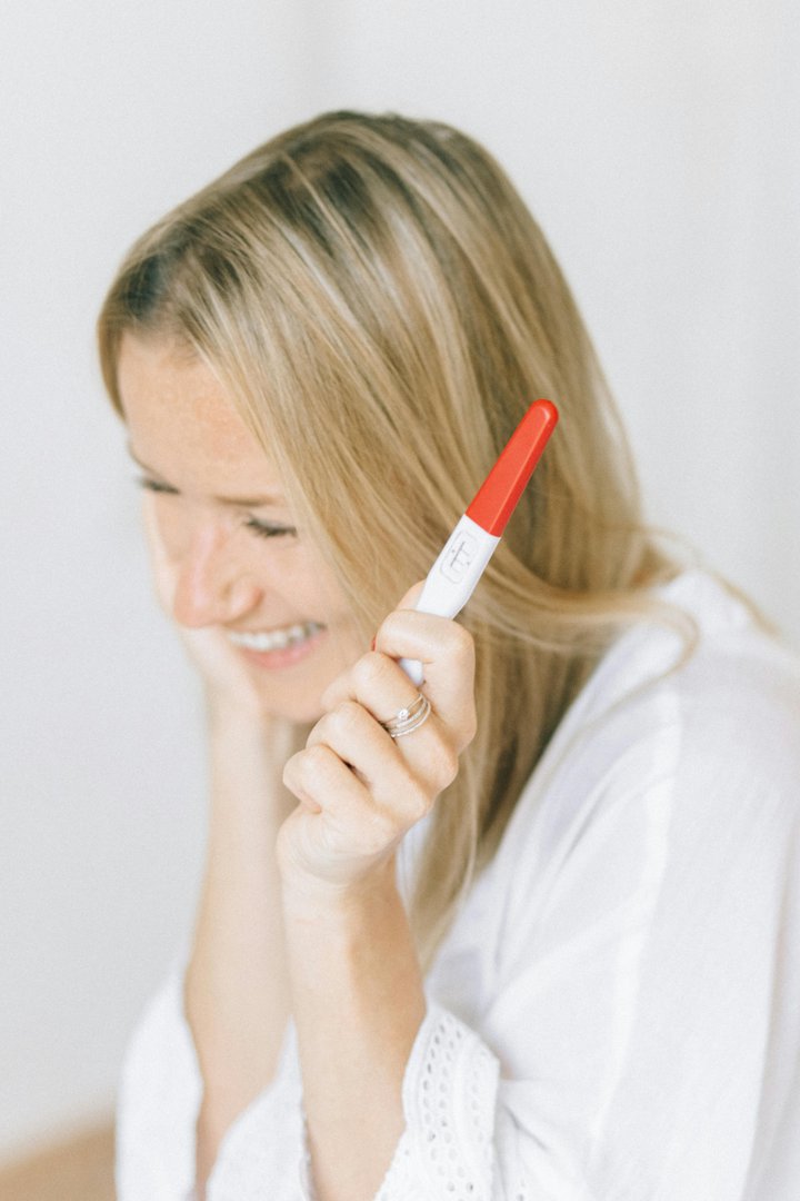 Happy woman holding a pregnancy test | Source: Pexels