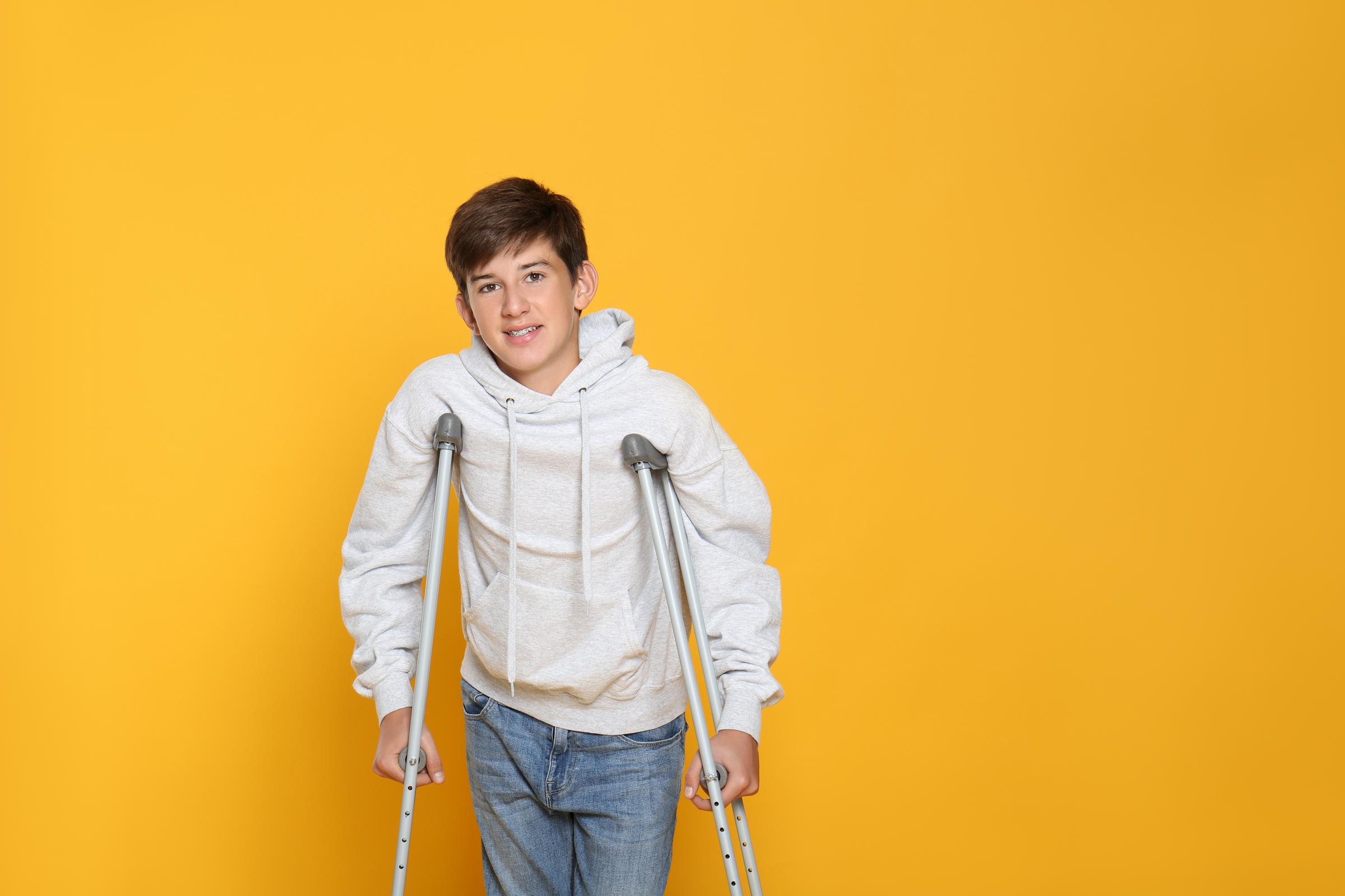 A teenage boy using crutches | Source: Shutterstock