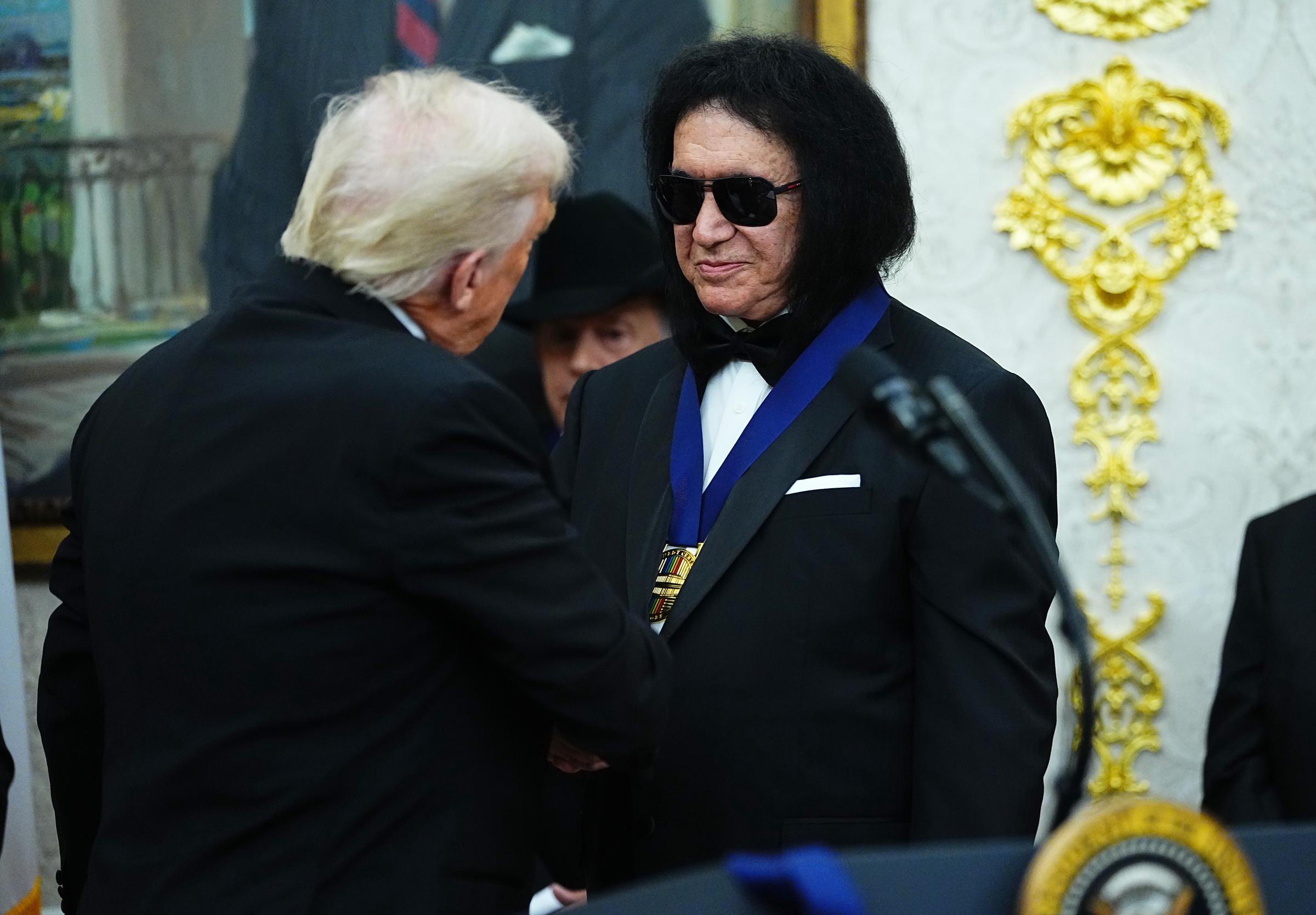 Donald Trump presents musician Gene Simmons (R) of the rock band KISS a medal for the Kennedy Center Honorees during a medal presentation in the Oval Office on December 6, 2025 in Washington, DC | Source: Getty Images