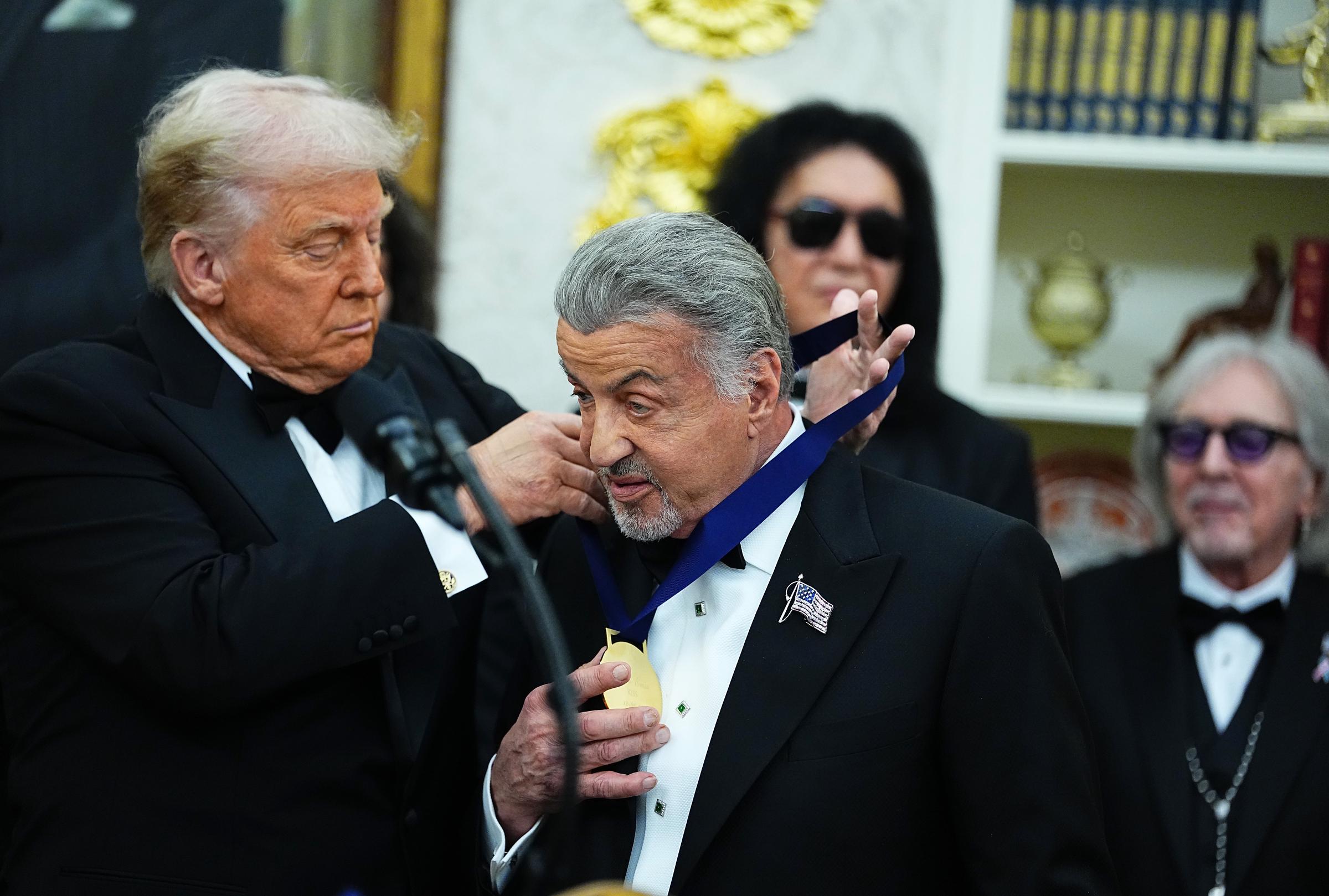 Donald Trump presents Sylvester Stallone a medal for the 2025 Kennedy Center Honorees during a medal presentation in the Oval Office on December 6, 2025 in Washington, DC | Source: Getty Images
