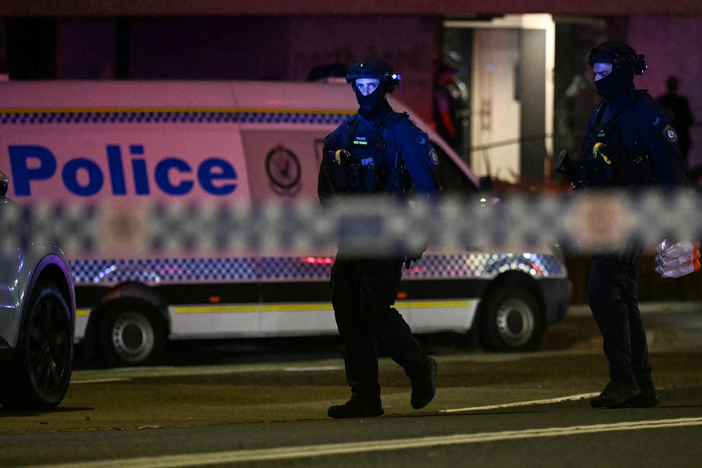 Heavily armed police stand guard near Bondi Beach after two gunmen launched a deadly attack during a Hanukkah celebration on December 14, 2025. The assault, which claimed the lives of 15 people and injured dozens more, unfolded as families gathered for the Jewish 