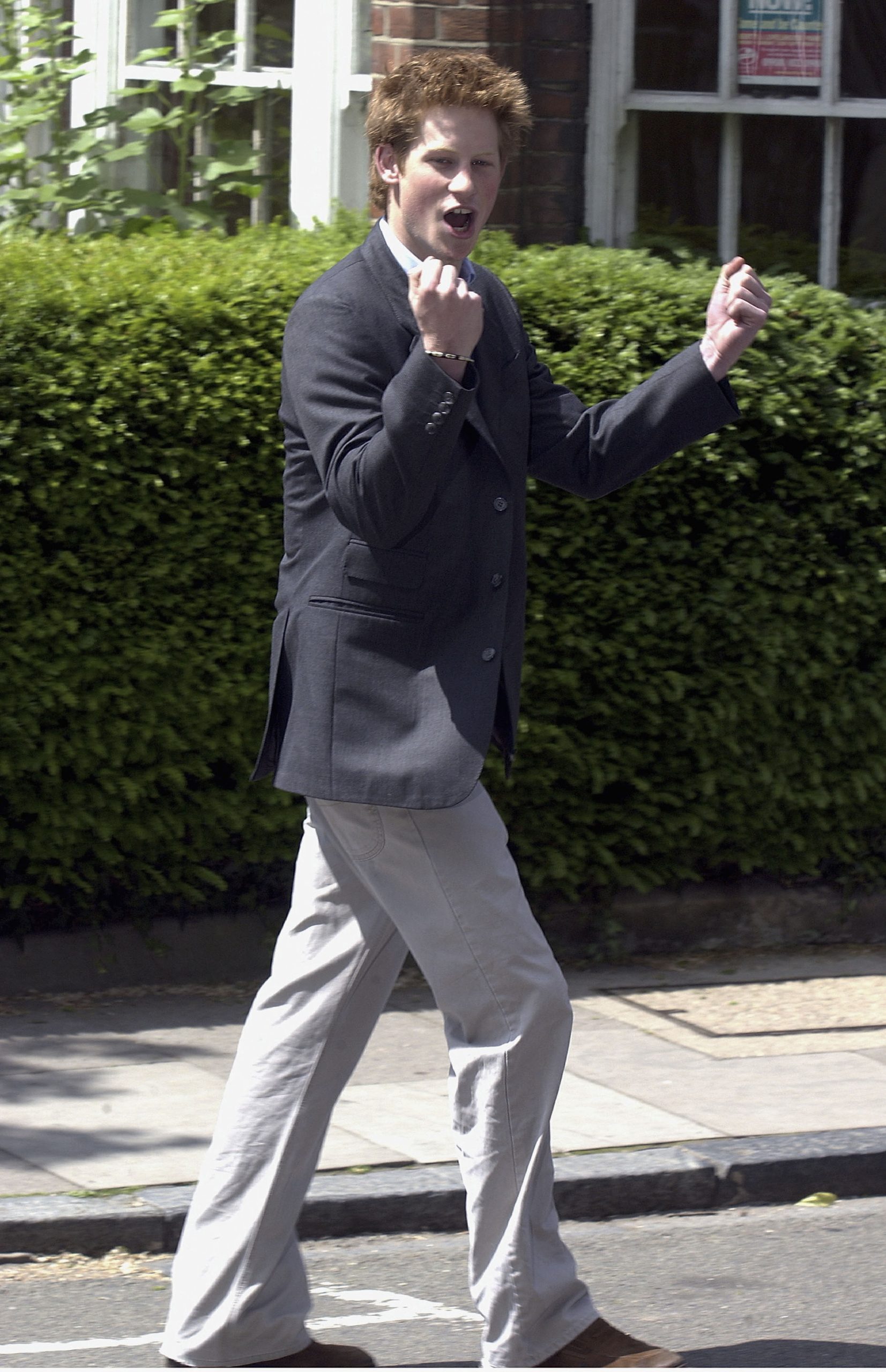 Prince Harry threw his fists in the air with visible glee as he walked away from Manor House on June 12, 2003, marking the end of his schooldays at Eton College. Dressed in a blazer and relaxed trousers, the 18-year-old prince was caught in a moment of unfiltered celebration — a symbolic close to one chapter and the carefree beginnings of another.