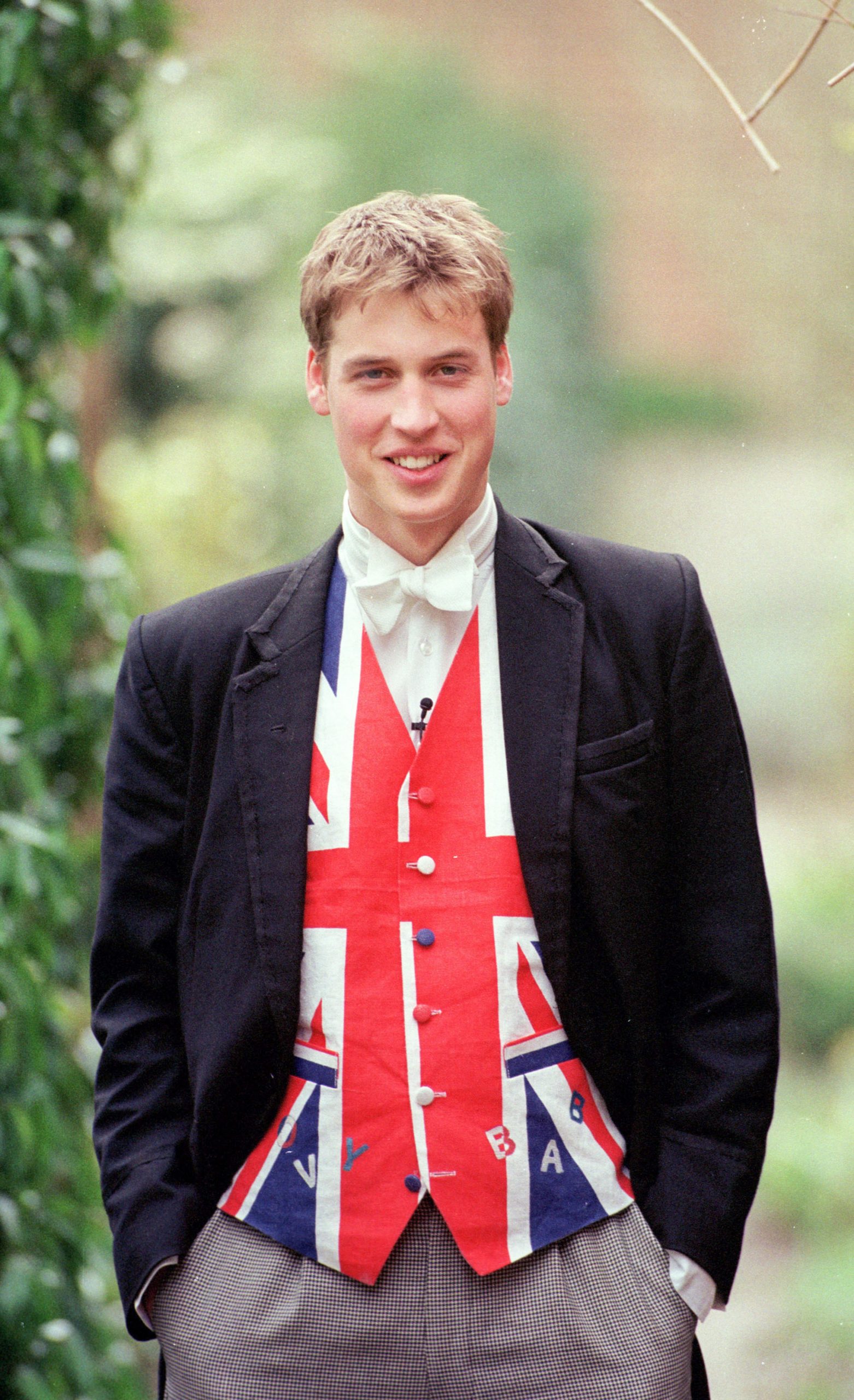In a striking show of youthful patriotism, Prince William dons a Union Jack waistcoat beneath a black tailcoat at Eton College in June 2000. Pictured as a prefect in his final year, the future king blends tradition with a flash of national flair.