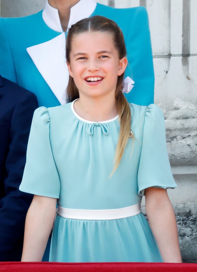 Glowing with joy, Princess Charlotte gazes skyward as an RAF flypast roars overhead from the balcony of Buckingham Palace during Trooping the Colour on 14 June 2025. Dressed in a soft aqua-blue ensemble with delicate detailing, she stands proudly alongside her family to mark King Charles III's official birthday.