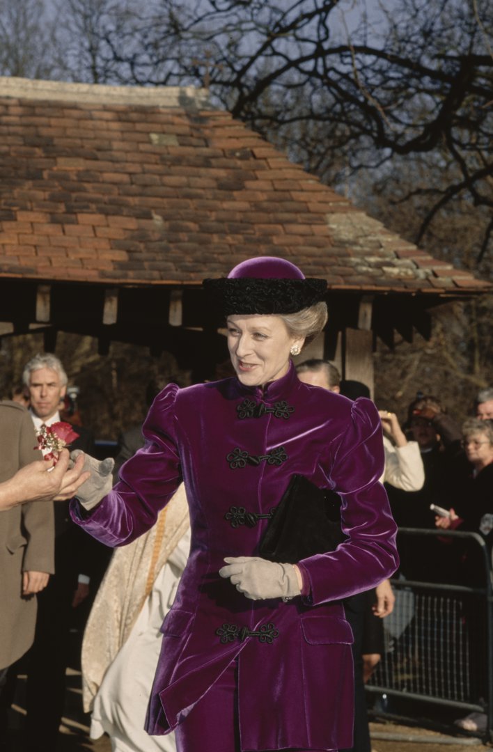 Dressed in rich purple velvet and a matching hat, Princess Alexandra arrives for the February 1990 wedding of her daughter, Marina Ogilvy. Acknowledging well-wishers with a composed smile, she steps into St Andrew's Church for a deeply personal family milestone.