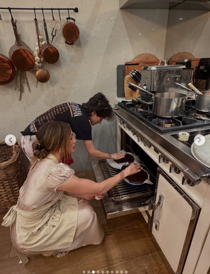 Jennifer Lopez and the young person beside her check on the cakes in the oven, as seen from a post dated November 28, 2025. | Source: Instagram/jlo