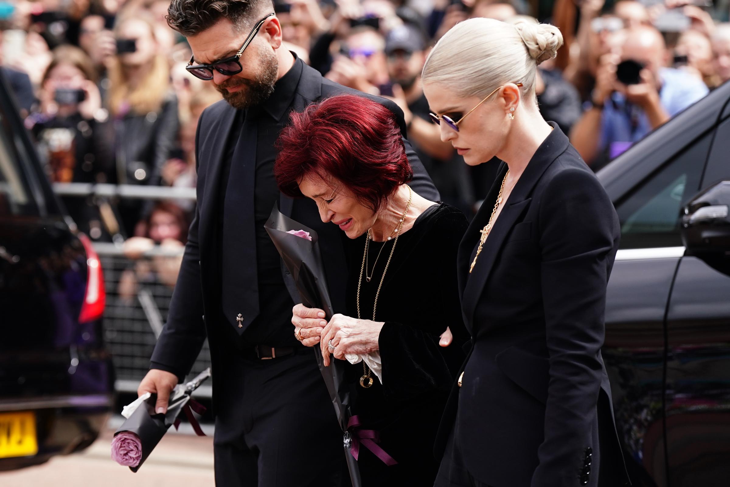 Sharon, Jack, and Kelly lay flowers at the Black Sabbath Bridge bench on Broad Street in Birmingham on July 30, 2025 | Source: Getty Images