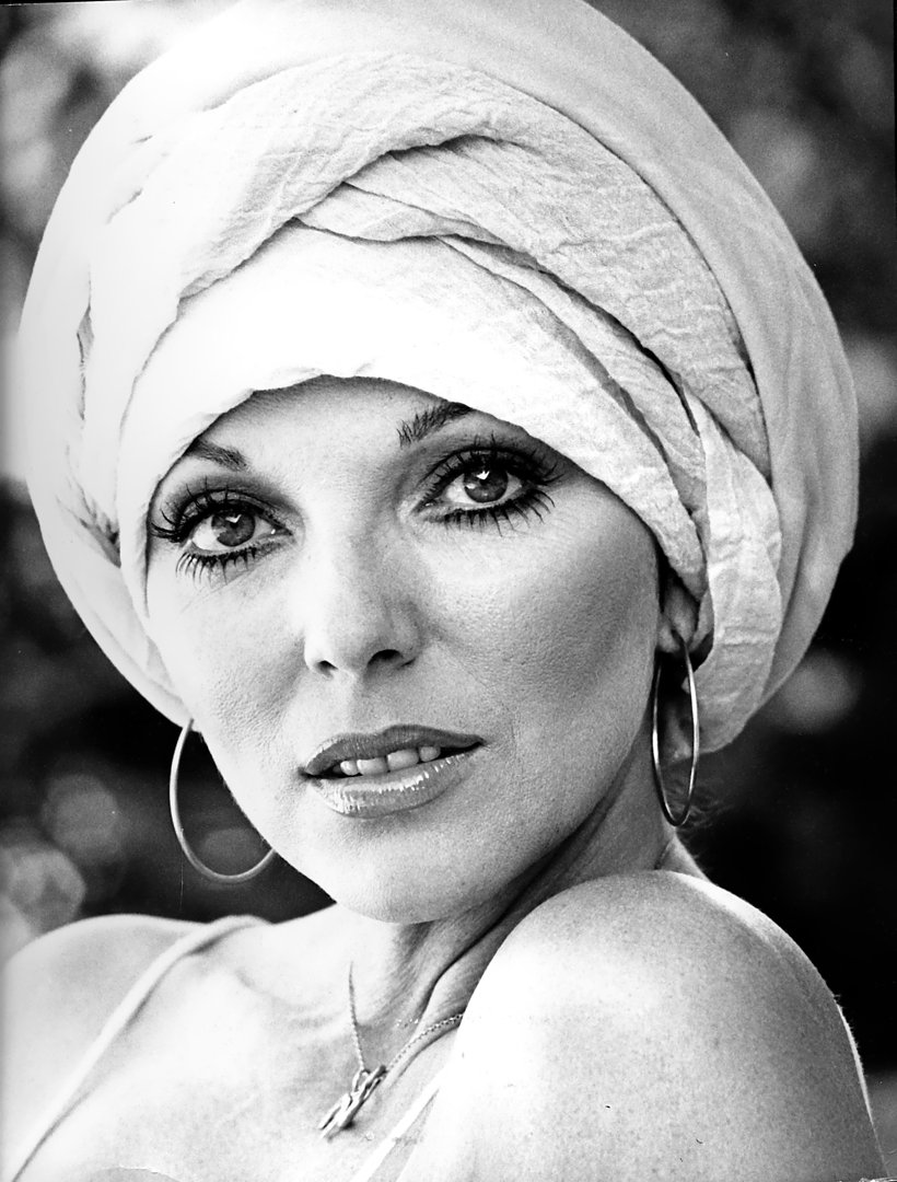 Photographed at her Beverly Hills home in June 1975, Joan Collins brought striking sophistication to this black-and-white portrait. Framed in a soft turban and oversized hoop earrings, she gazed directly into the lens with quiet confidence. The natural lighting and pared-back styling offered a glimpse of Collins's off-screen elegance during a transitional period in her career.