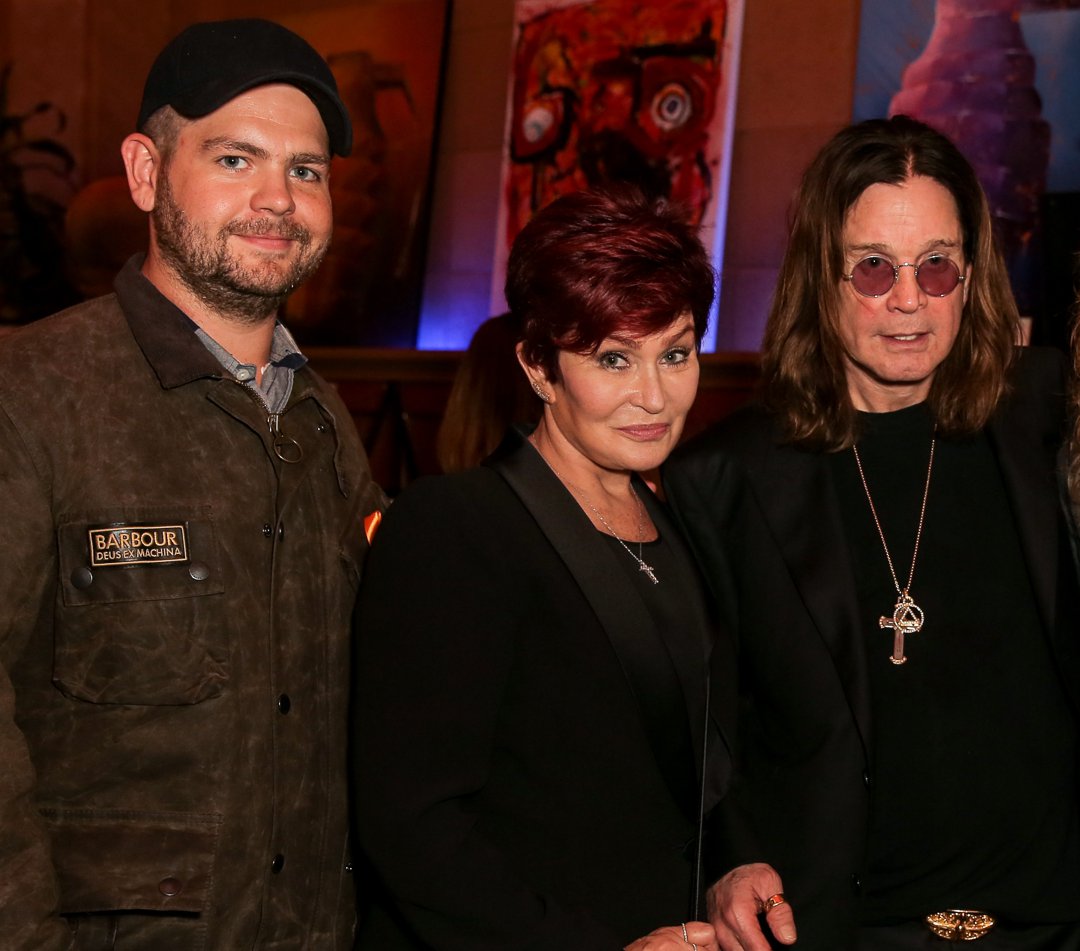 Jack Osbourne joins his parents Sharon and Ozzy for a photo at an event in Los Angeles, the trio standing close together in front of a display of vibrant artwork.