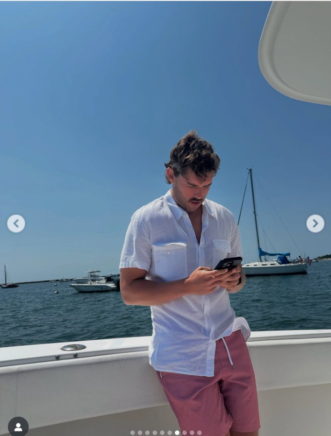 Christopher Schwarzenegger stands on a boat, looking at his phone, from a post dated August 23, 2025 | Source: Instagram/katherineschwarzenegger