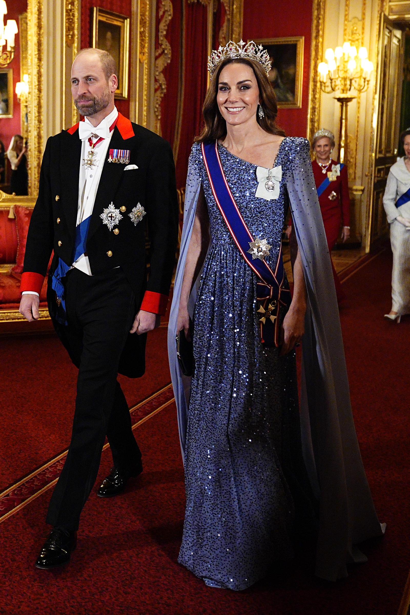 William, Prince of Wales, and Catherine, Princess of Wales, made a striking entrance at Windsor Castle. The Princess dazzled in a floor-length, lavender-blue gown adorned with sequins and finished with a regal cape and tiara, while the Prince wore full evening dress and ceremonial honours — both embodying the grandeur and tradition of royal diplomacy.