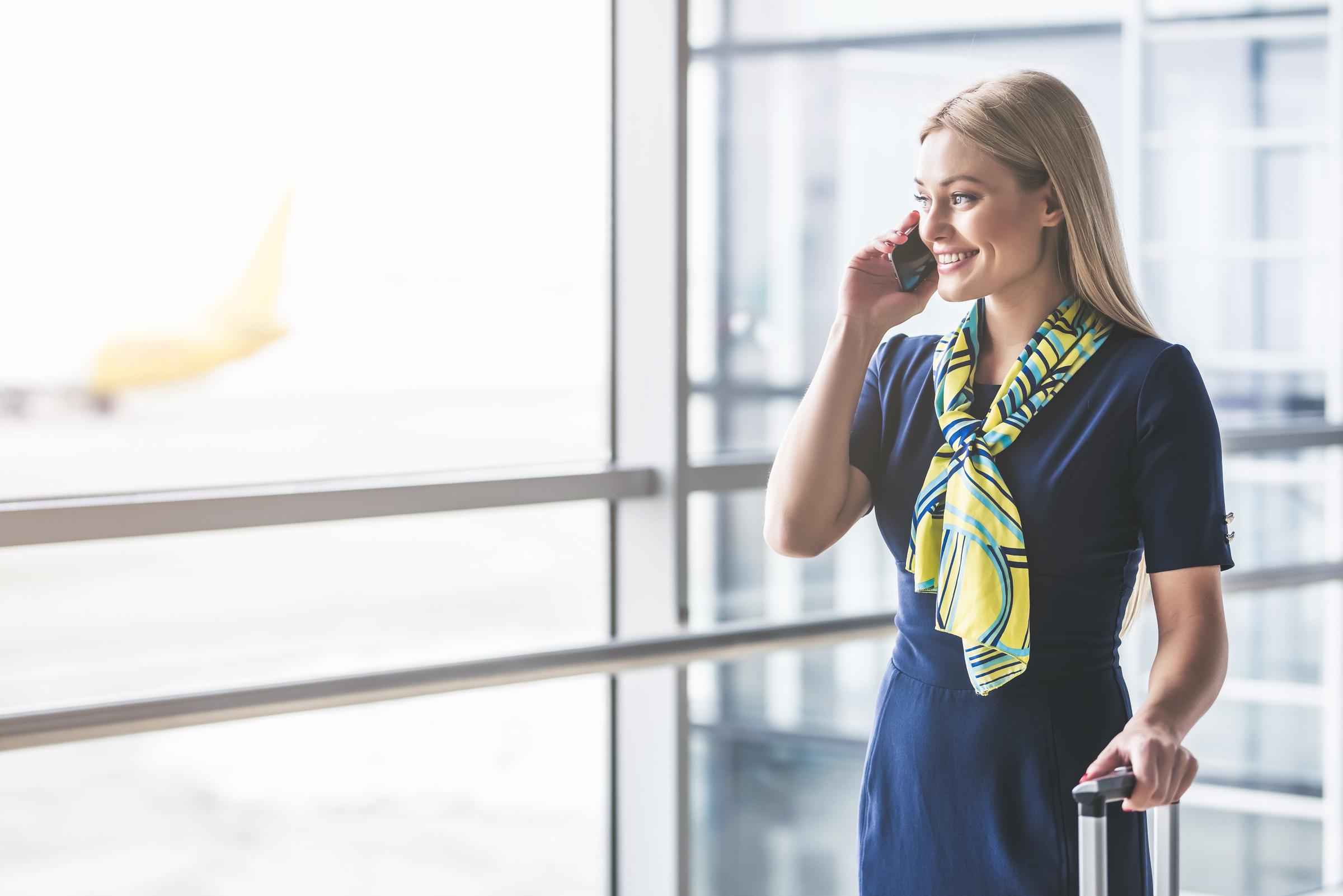 Flight attendant on phone | Source: Shutterstock