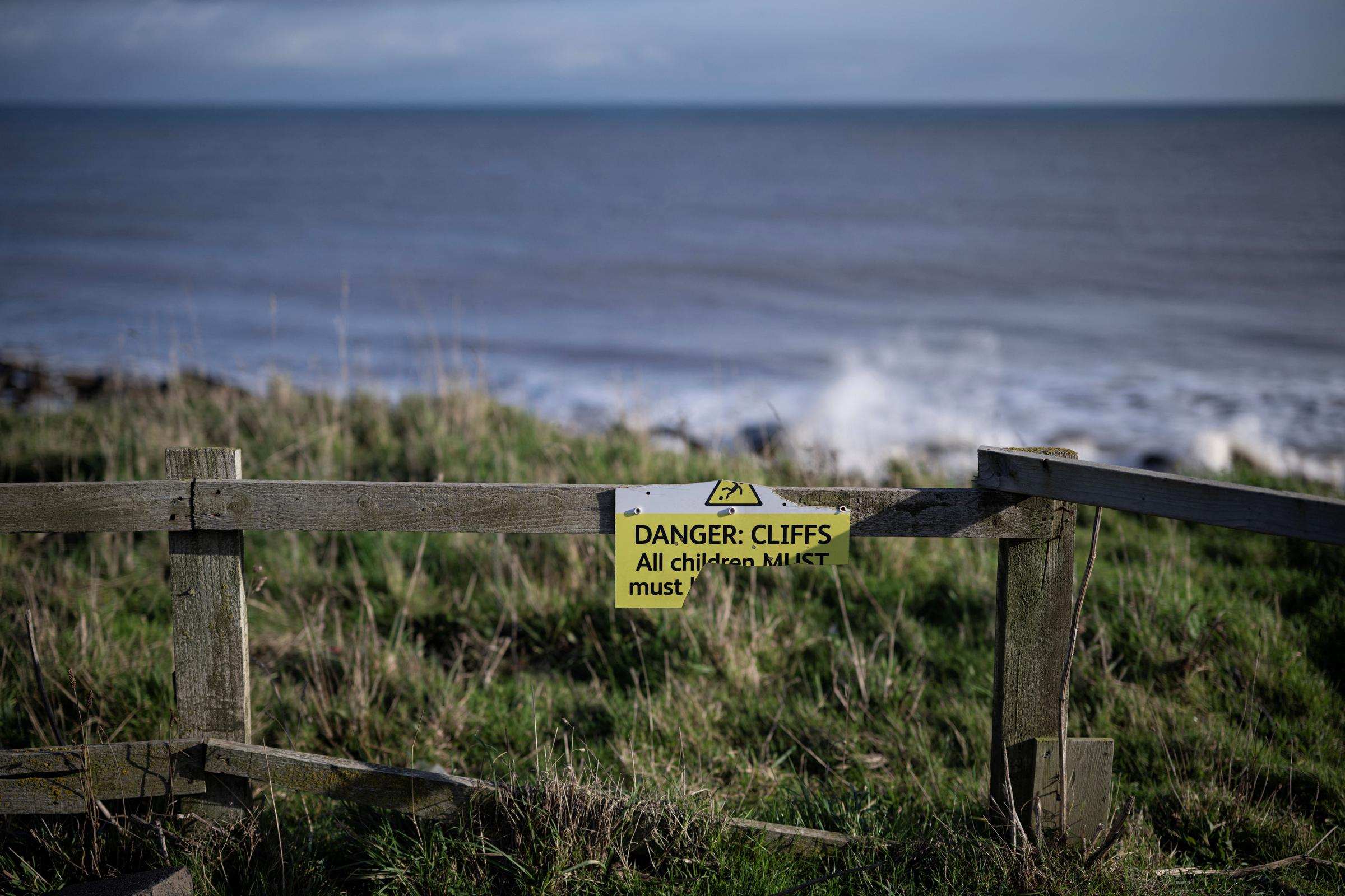 A damaged notice warning of the dangers of collapsing cliff edges attached to fencing on the North Sea coast photographed on November 13, 2025. | Source: Getty Images
