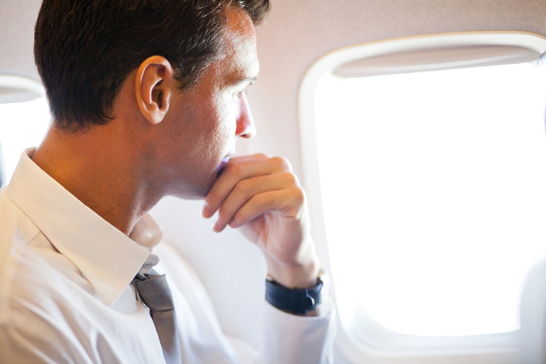 Serious businessman inside a plane looking outside the window | Source: Shutterstock