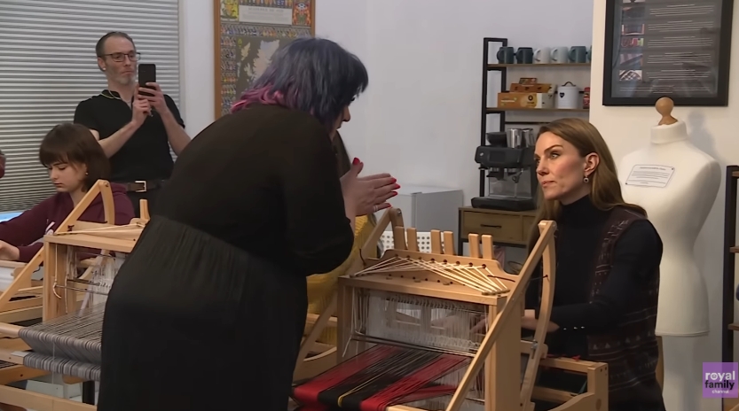 Princess Kate was seen seated at a loom inside Radical Weavers, attentively listening to a staff member explain the weaving process. Surrounded by looms and participants of all ages, the Princess was fully engaged with the charity's hands-on approach to preserving traditional Scottish crafts. | Source: YouTube/The Royal Family Channel