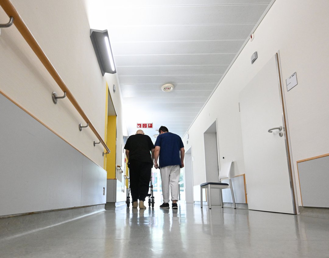 A nurse walks across the corridor with a patient on a ward in a hospital. | Source: Getty Images