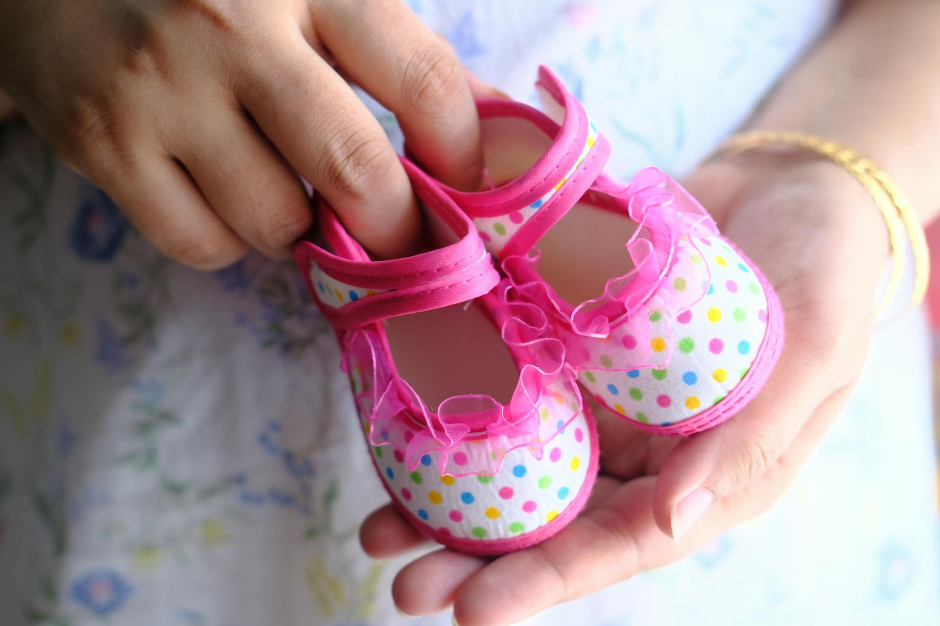 A woman holding pink baby shoes | Source: Pexels