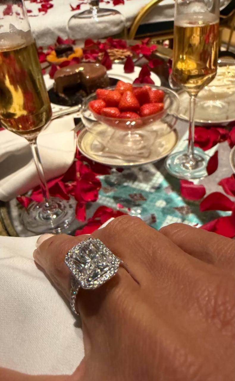 She gave fans an up-close flash of the jaw-dropping diamond ring, with the square-cut centre stone and halo sparkle stealing the show as champagne, strawberries, and petals completed the over-the-top setup. | Source: Instagram/katieprice