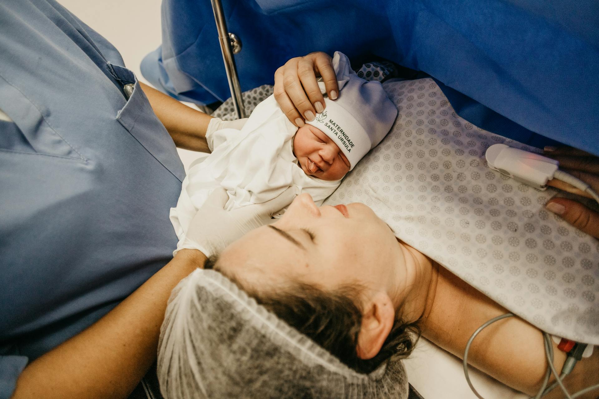 A newborn baby beside a woman in a hospital room | Source: Pexels