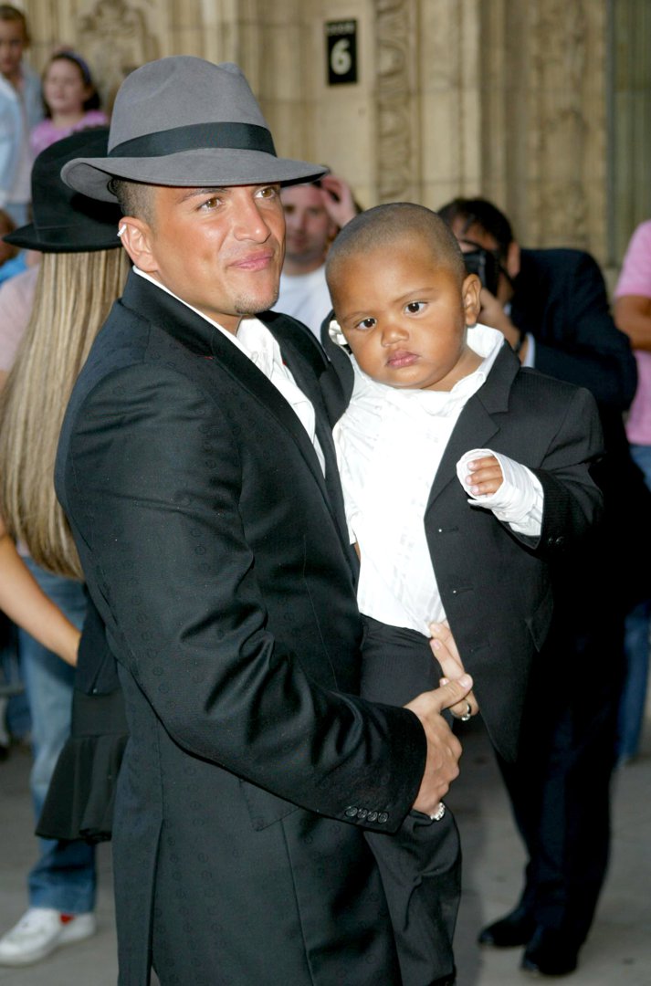 A suited Peter Andre holds a young Harvey Price close at the 2004 Disney Channel Kids Awards in London. The affectionate moment captured the early bond the pair shared, as Peter took on a fatherly role during his romance with Katie Price, who can be seen just behind them in matching black.