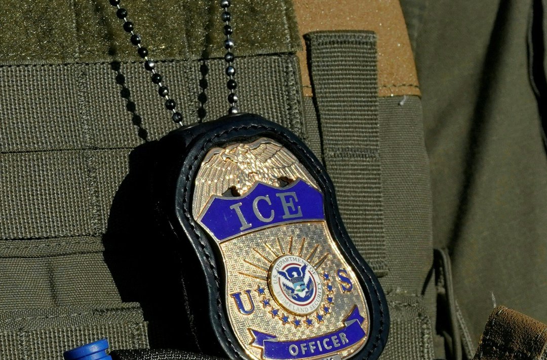 An ICE officer's badge is shown attached to a tactical vest | Source: Getty Images