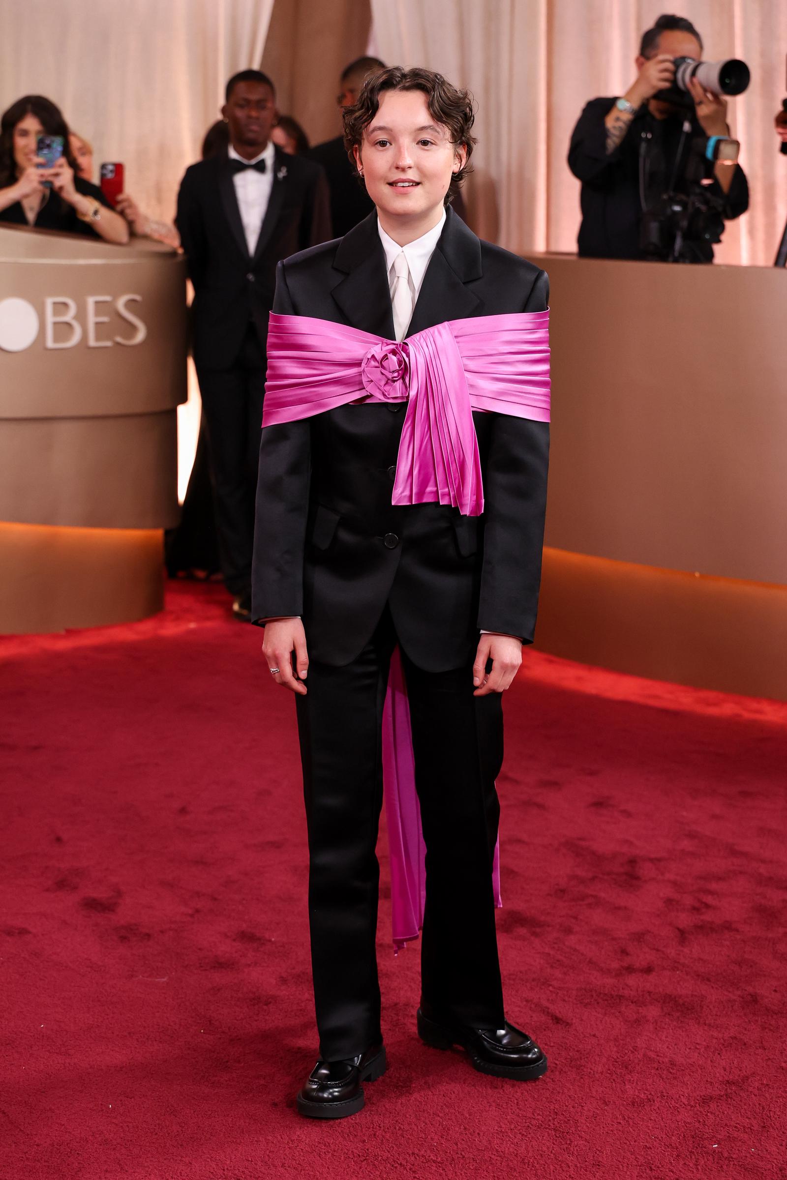 Bella Ramsey Dazzles in Bold, Tailored Glamour: Bella Ramsey turned heads on the red carpet at the 83rd Annual Golden Globes at The Beverly Hilton, commanding attention in a sharply tailored black suit finished with a striking pink bow accent. A fearless twist on classic formalwear &mdash; and a fashion moment to remember. | Source: Getty Images