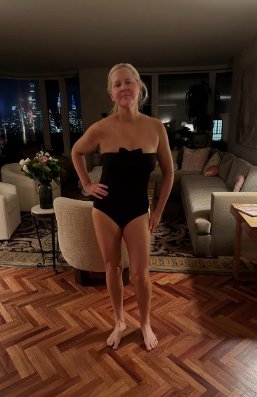 In a fitted black strapless swimsuit with a subtle bow detail, Amy Schumer stood confidently in her living room, revealing a leaner figure and noticeably smaller waist. Her arms and legs appeared more defined, marking a dramatic shift from previous public appearances. | Source: Instagram/amyschumer