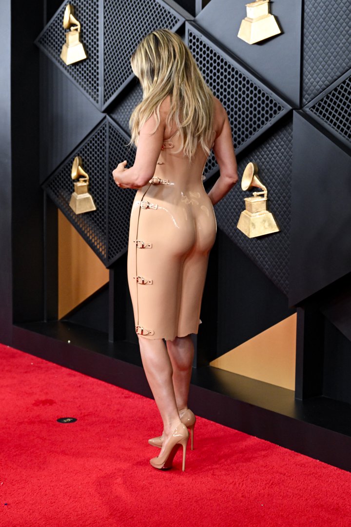In a separate moment on the carpet, Klum turns slightly to the side, offering a different angle of the same skin-toned ensemble. The lighting highlights the sheen of the fabric and the precise tailoring of the dress, with the side detailing and silhouette more clearly defined as she paused for cameras against the Grammys backdrop.