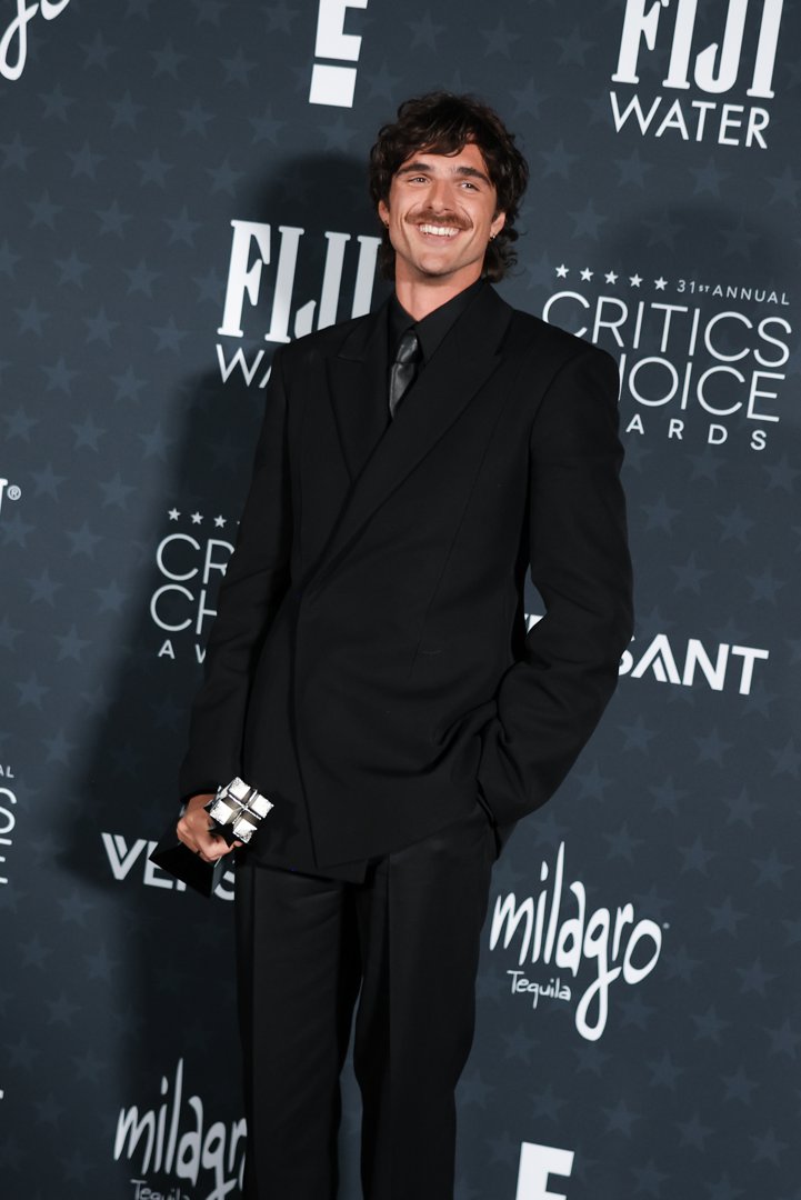 Jacob Elordi poses backstage in a classic black suit after winning Best Supporting Actor, holding his award with a smile | Source: Getty Images
