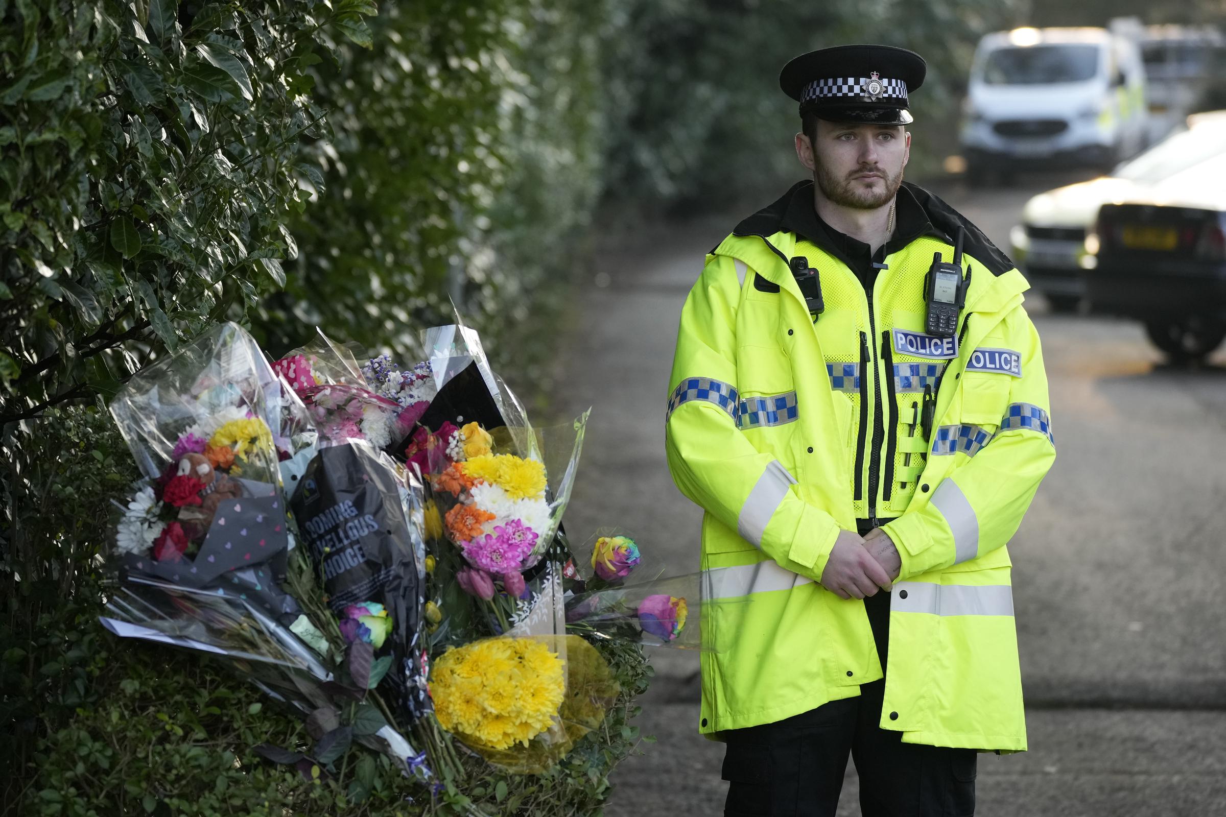 A police officer standing next to floral tributes at the entrance to Linear Park on February 13, 2023, in Warrington, England. | Source: Getty Images
