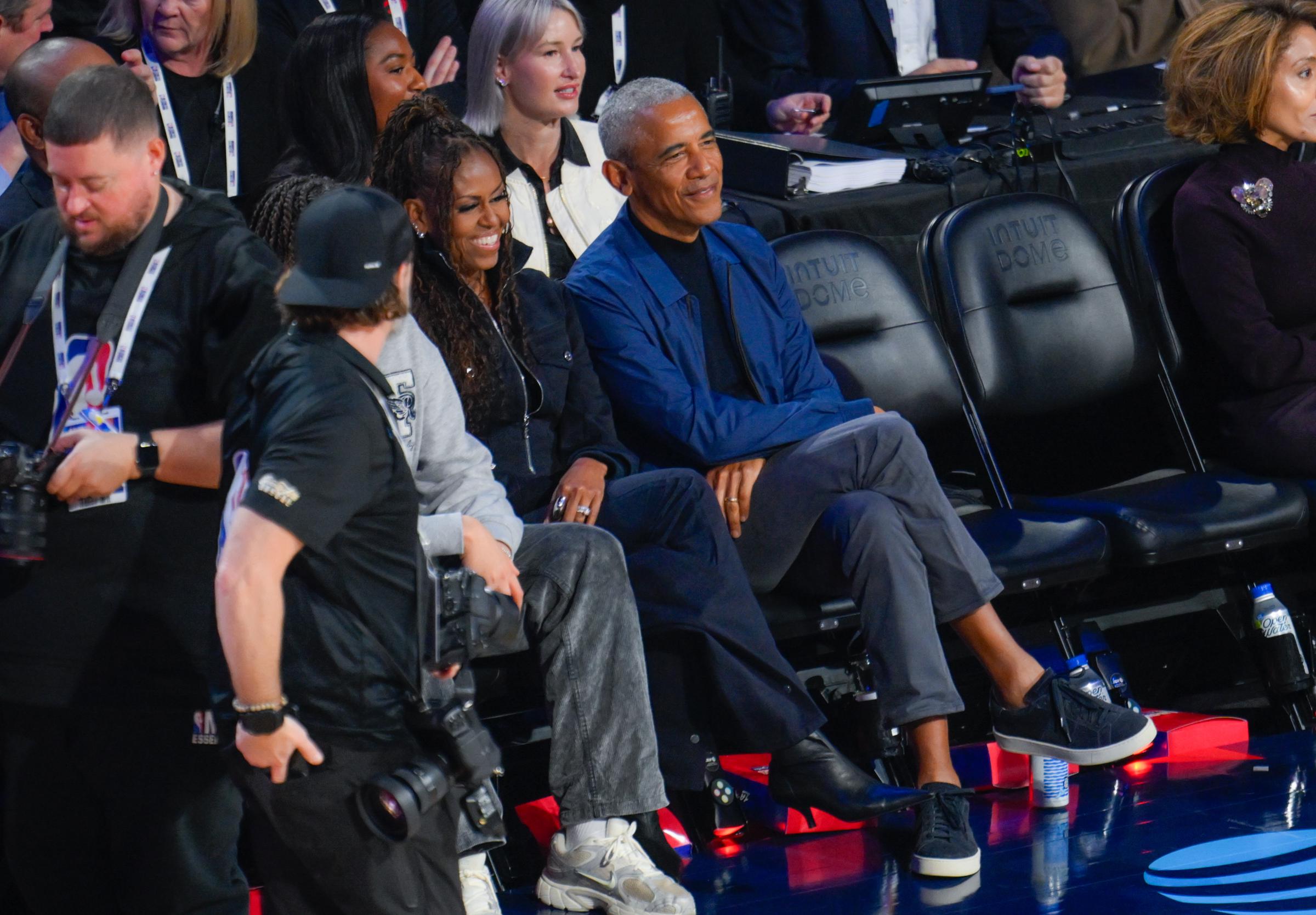 Michelle and Barack Obama observing the game with their daughter, Sasha Obama, seated behind them. | Source: Getty Images