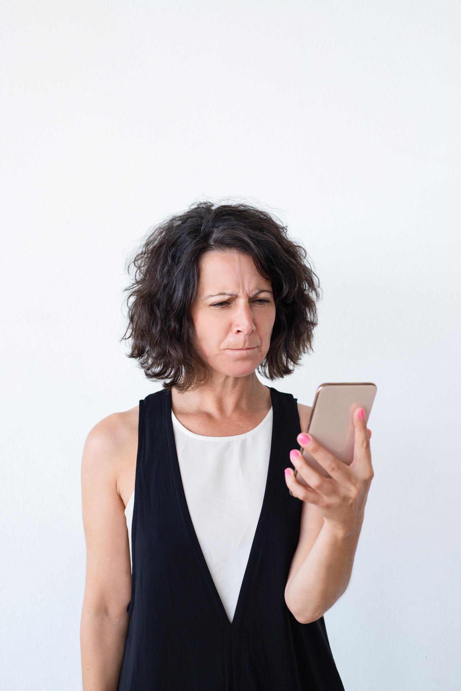 An annoyed woman looking at her phone | Source: Freepik