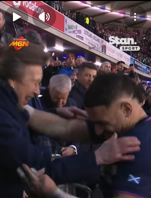 The moment resolves with a light touch to the shoulder and a shared grin, Sione Tuipulotu lowering his head slightly as the Princess Royal steadies the interaction and the trophy remains secure. Around them, teammates and officials look on, the Calcutta Cup presentation continuing with dignity intact despite the near-embrace. | Source: YouTube/StanSportAU