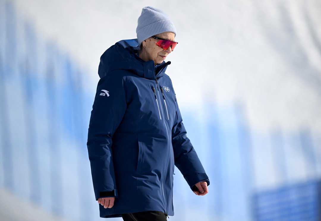 Princess Anne, Princess Royal, cut a solitary figure against the pale sweep of Livigno Snow Park as she looked on following the Women's Slopestyle Final on February 9, 2026. Wrapped in a deep navy technical coat and a soft grey beanie, she leaned into the Alpine chill with quiet focus, while her mirrored red sunglasses flashed sharply against the snow.
