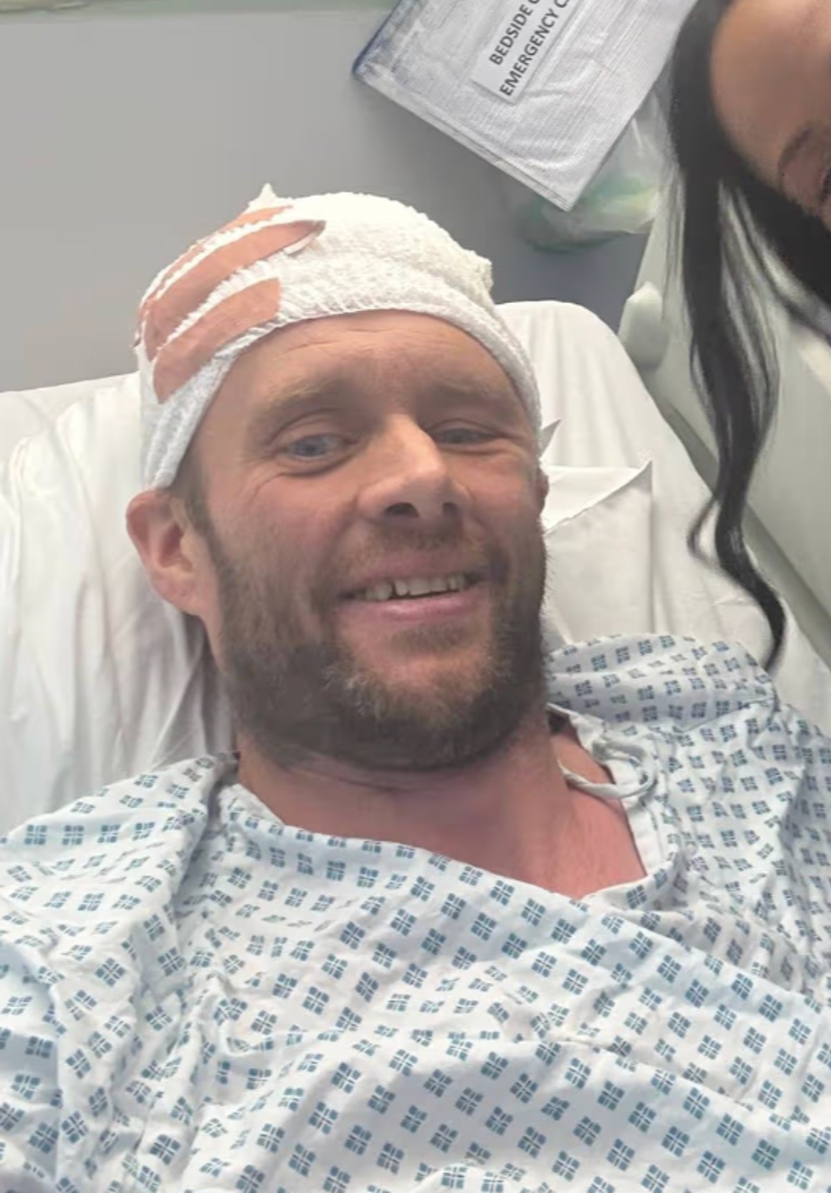 A Warrior's Smile: From his hospital bed, Smith offers a brave, defiant smile despite the visible bandaging from brain surgery. With just four months to live, the gold medallist faces his toughest battle yet &mdash; and the world watches in awe at his unbreakable spirit. | Source: Facebook/Daily Record