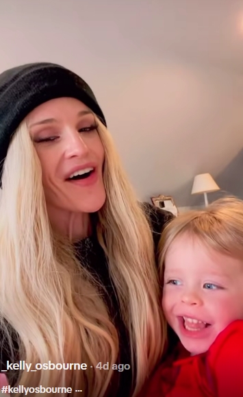 In a second still from the same light-hearted clip, Osbourne appears to be mid-sentence, her expression animated as her son looks slightly off-camera, smiling with rosy cheeks. The candid frame captures the playful dynamic between them, suggesting the gentle prompting that led to their shared