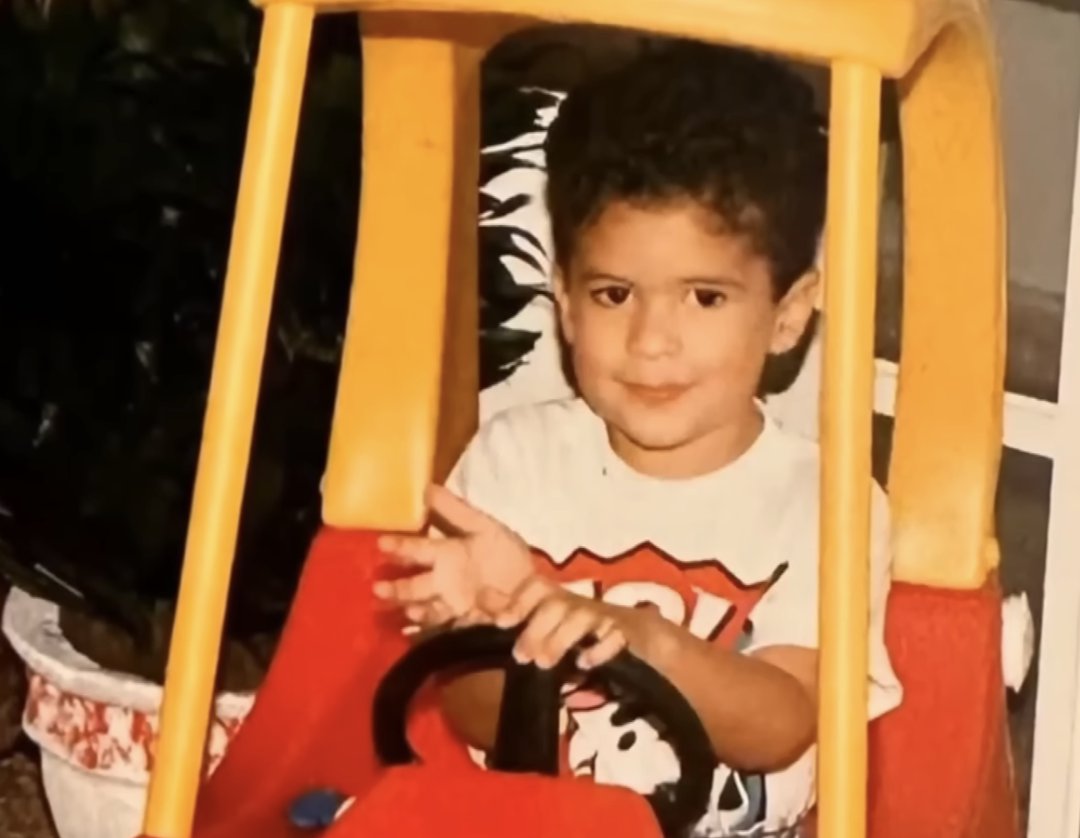 A younger Bad Bunny drives a toy car, A young Bad Bunny smiles at the camera as he sits in a chair, from a post dated August 31, 2025. | Source: YouTube/TODAY