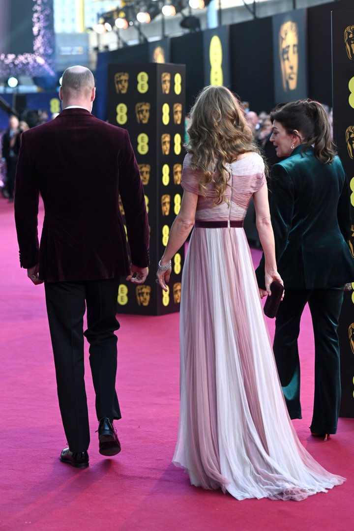 From behind, the Prince and Princess of Wales walked the length of the pink carpet at the Royal Festival Hall, their silhouettes framed by the iconic BAFTA masks. The flowing layers of the Princess's blush-toned gown trailed softly behind her, while the Prince's deep maroon velvet jacket stood out against the dark backdrop as they made their entrance on February 22, 2026.
